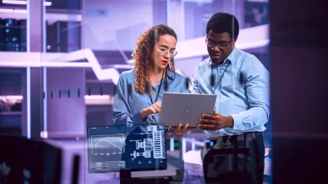 Image of officemates discussing while holding a laptop