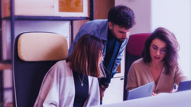 Coworkers collaborating around a laptop in a modern workspace