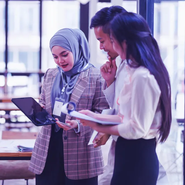Image of Muslim woman showing tablet to officemates