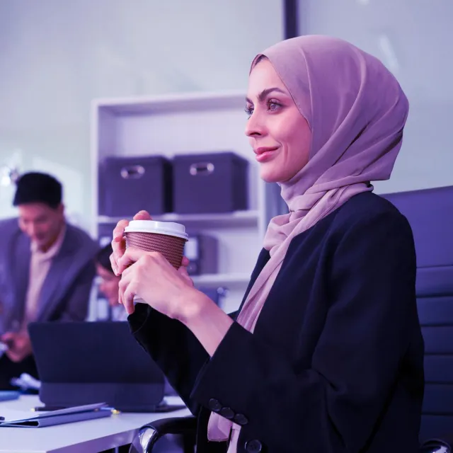 Image of Muslim woman holding coffee in office desk