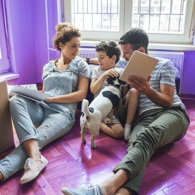 Family relaxing at home with a tablet while unpacking boxes