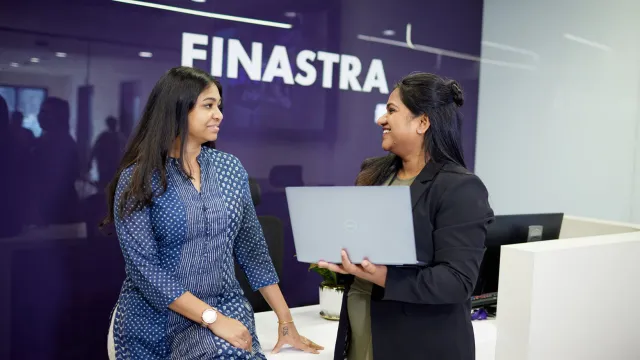 Image of two women talking in front of a Finastra logo