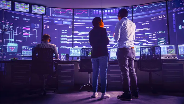 Network operations center team monitoring real‑time system dashboards on multiple screens