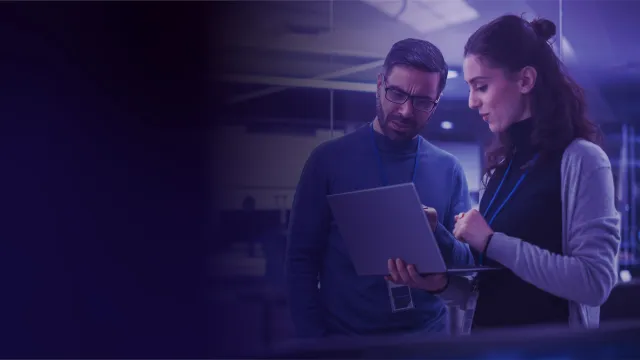 Two professionals reviewing data on a tablet in a modern data center.