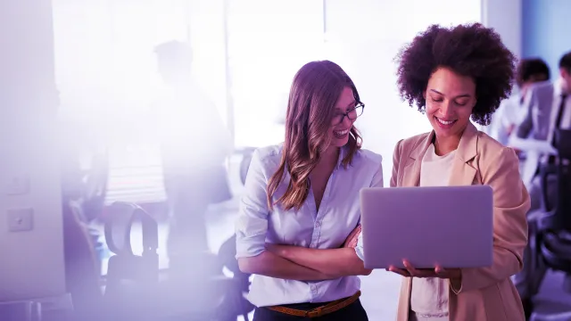 Two professionals collaborating on a laptop in a modern corporate office workspace