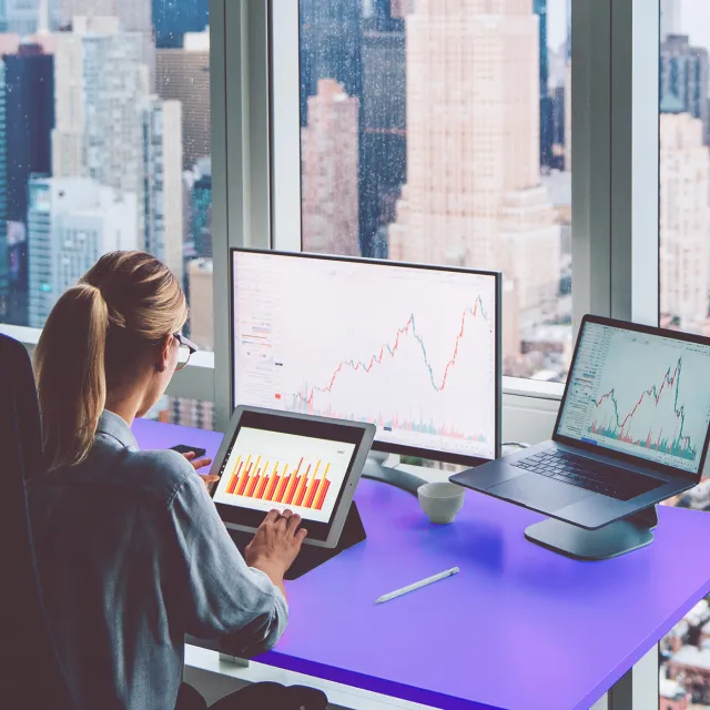 Woman analyzing payments trends in her multi-screen workstation