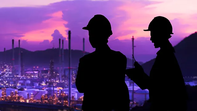 Image of two persons wearing hard hats with cityscape in the background