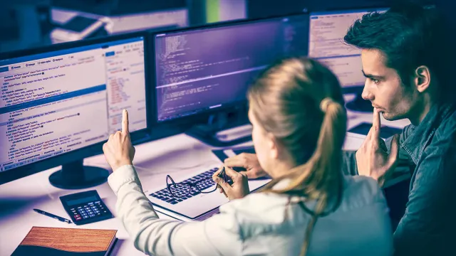 Image of two officemates discussing in their desks