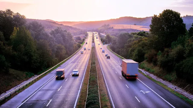 Freight trucks and vehicles traveling on a major highway, representing connected networks, commerce, and efficient movement across regions.