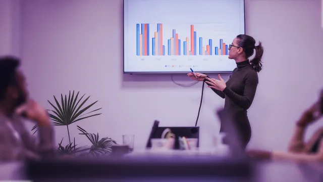 Image of woman presenting bar charts to team