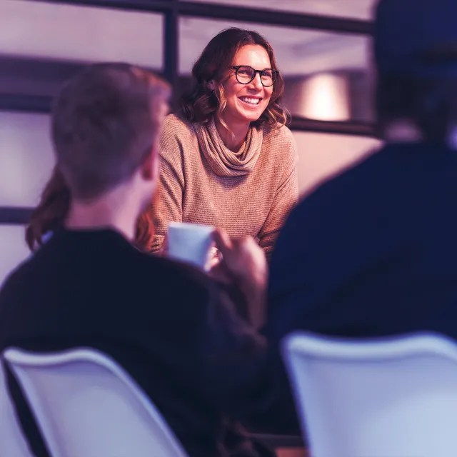 Image of woman standing and smiling in front of team