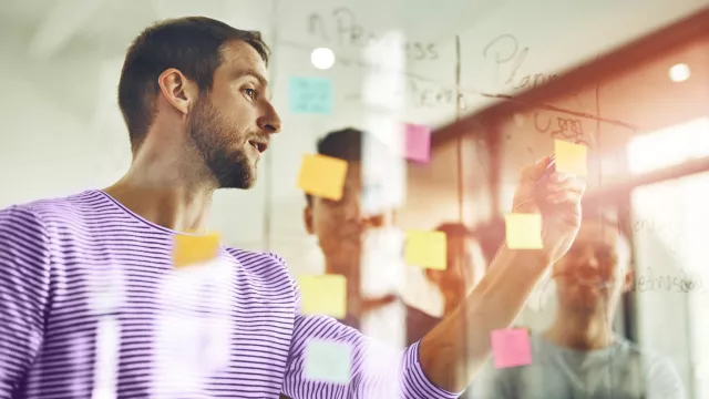 Man writing on glass with post-it