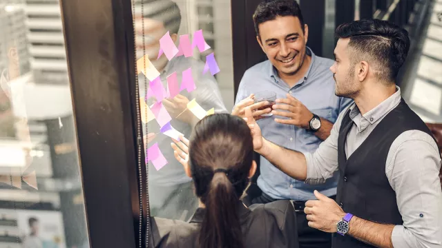 Image of 3 people with post-it notes on window