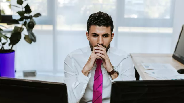 Image of man looking at two computer screens