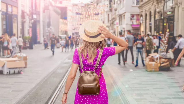 Woman with backpack hoding hat on head