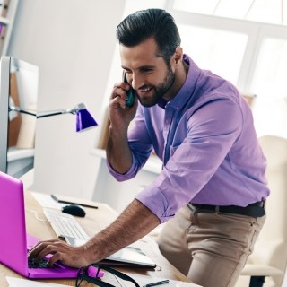 Man working from home on laptop with cell phone