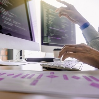 Person pointing at computer screen with data