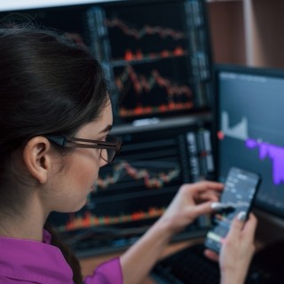 Woman working on phone with multiple monitors