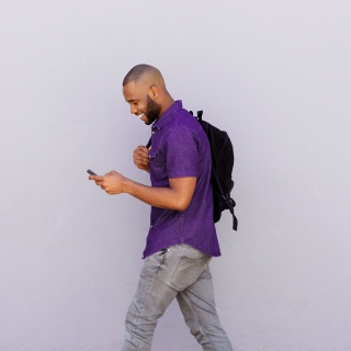 Image of a man on phone, walking and smiling