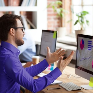 Image of man explaining graph in monitor to officemate