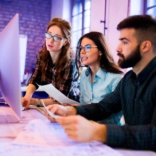 Image of team discussing in front of a computer
