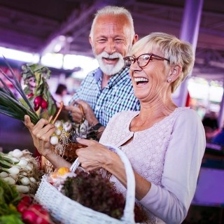 Image of elderly couple buying vegetables in a market