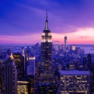 Twilight cityscape of New York City with the Empire State Building and skyline glowing at sunset.
