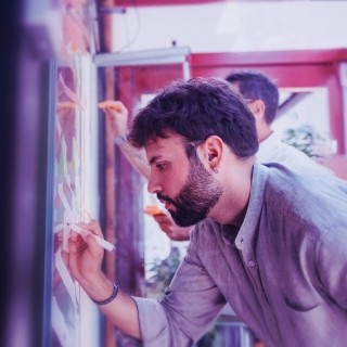 Coworkers brainstorming with sticky notes on a glass board in a modern office.
