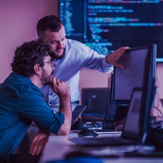 Developers collaborating on code review and debugging in a modern programming workspace.