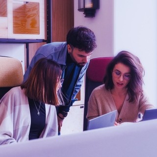 Coworkers collaborating around a laptop in a modern workspace