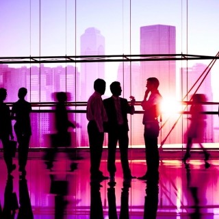 Business professionals in a modern office with city skyline at sunset.