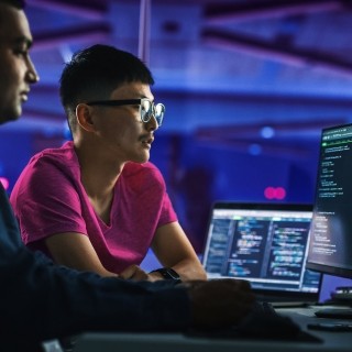 Cybersecurity experts analyzing code on multiple monitors in a high-tech environment.
