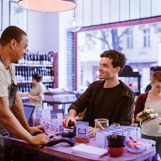 Customers making purchases at a local store counter in a modern retail environment.