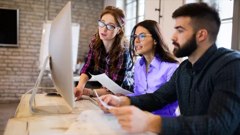 Image of team discussing in front of computer