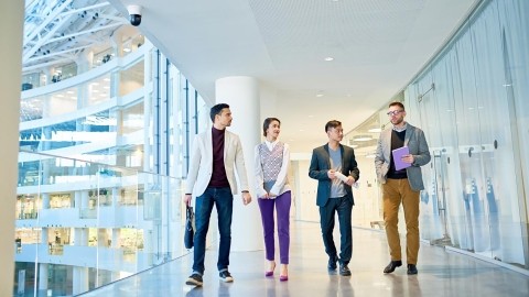 Image of officemates walking and discussing in office hallway