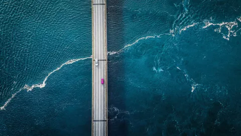 Image of two cars on a bridge over the ocean