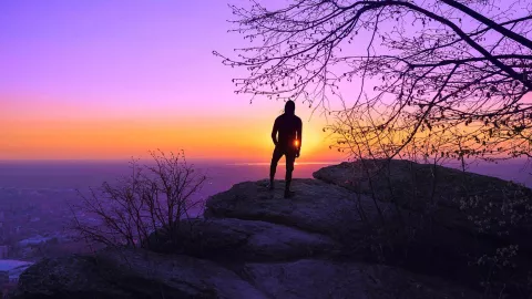 Image of a man standing near the edge of a cliff looking over the horizon