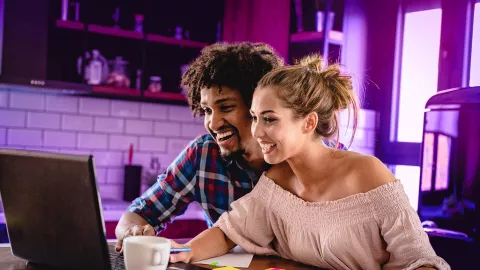 Image of couple smiling while looking at the laptop in the kitchen