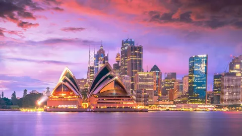The iconic Sydney Opera House at sunset with a vibrant city skyline