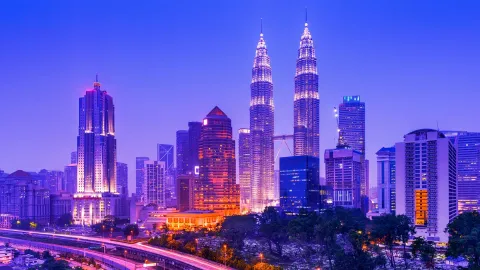 Kuala Lumpur city skyline at dusk with illuminated Petronas Twin Towers.