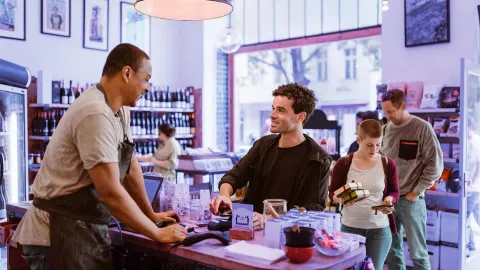 Customers making purchases at a local store counter in a modern retail environment.