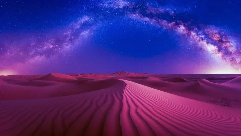 Vibrant pink desert dunes under a stunning Milky Way galaxy night sky with vivid stars and cosmic arc.