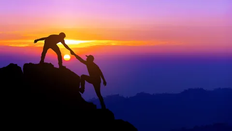Image of mountain climbers helping each other on an afternoon hike