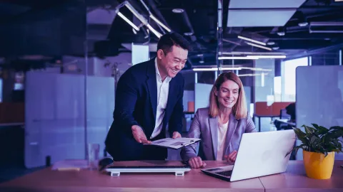 Image of two officemates discussing while looking at a laptop