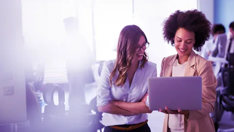 Two professionals collaborating on a laptop in a modern corporate office workspace