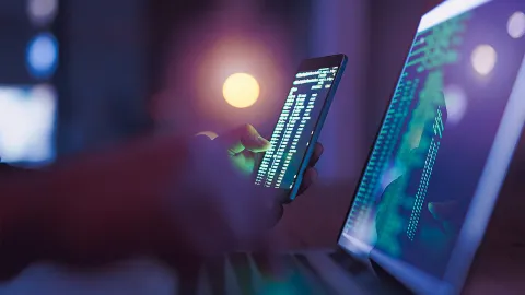 Encrypted data streams displayed on smartphone and laptop screens in a dark cybersecurity environment