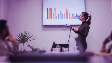 Image of woman presenting bar charts to team