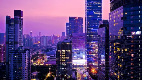 Modern city business district with illuminated high-rise office buildings at dusk.