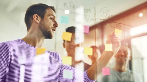 Man writing on glass with post-it