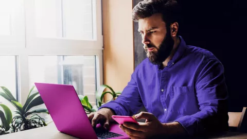 Man with laptop and phone by window